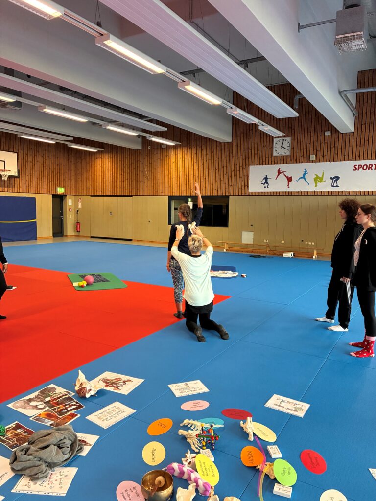 Rückblick Netzwerktreffen März 2026: Der "bewegte Weg zur Achtsamkeit" im Rehasport 5 Christiane zeigt Bewegung vom Schulterblatt an einer TN - Rückblick Netzwerktreffen März 2026: Der "bewegte Weg zur Achtsamkeit" im Rehasport
